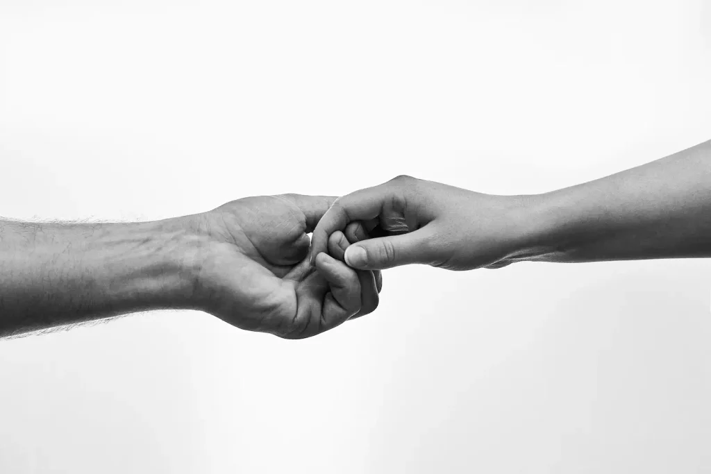 Intended parents holding hands with a newborn baby, illustrating the trusted matching program and premium care at Delicate Touch Surrogacy Agency LLC in Missouri.